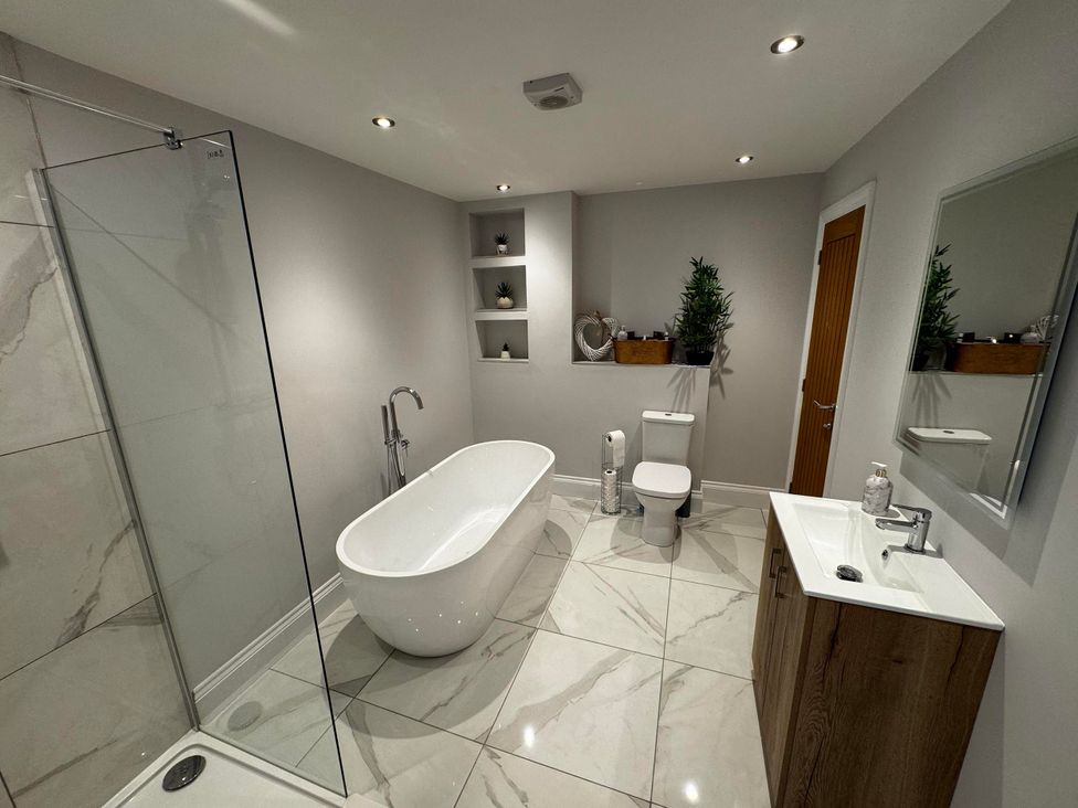 A bathroom with a bathtub, shower, and sink at Courtenay House, Harpham near Nafferton