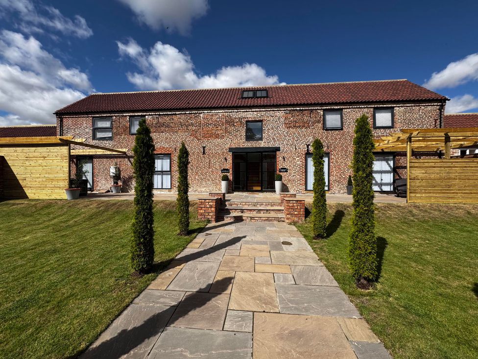A brick house with a garden and pathway at Courtenay House Harpham near Nafferton