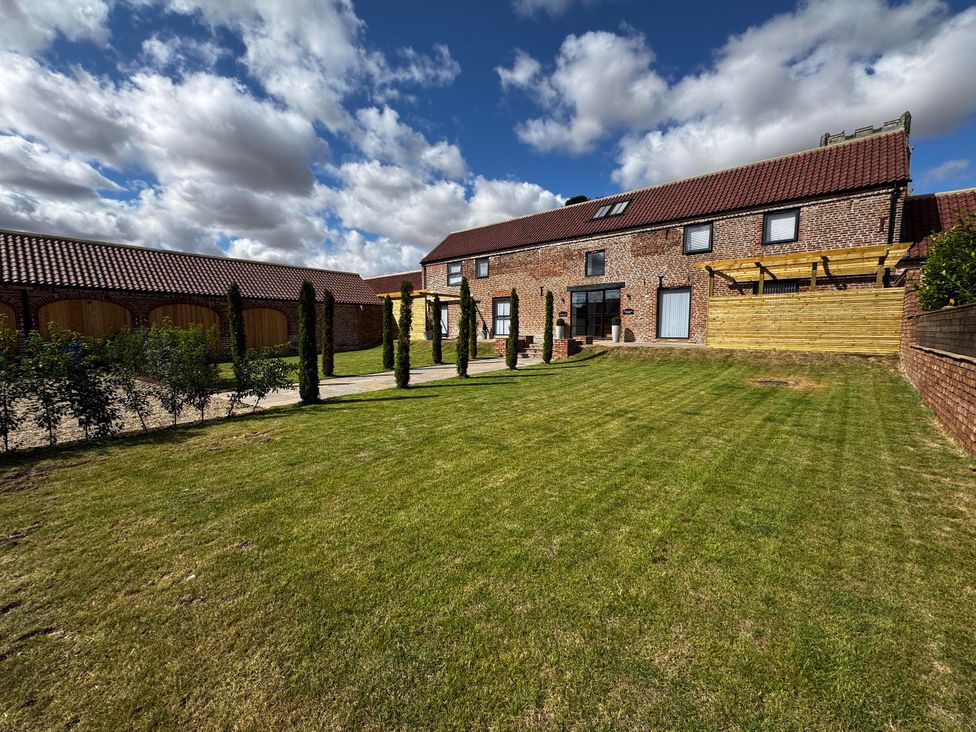 A garden with a house and pathway at Courtenay House in Harpham near Nafferton