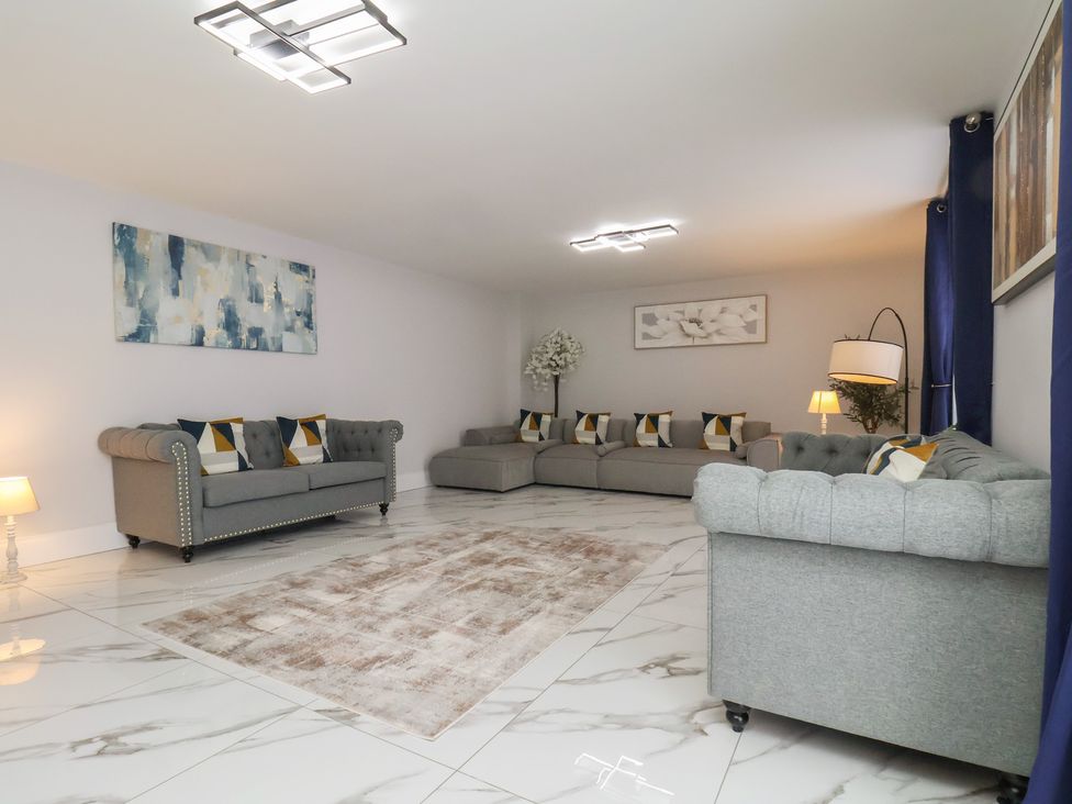 A living room with gray sofas and a lamp at Courtenay House in Harpham near Nafferton