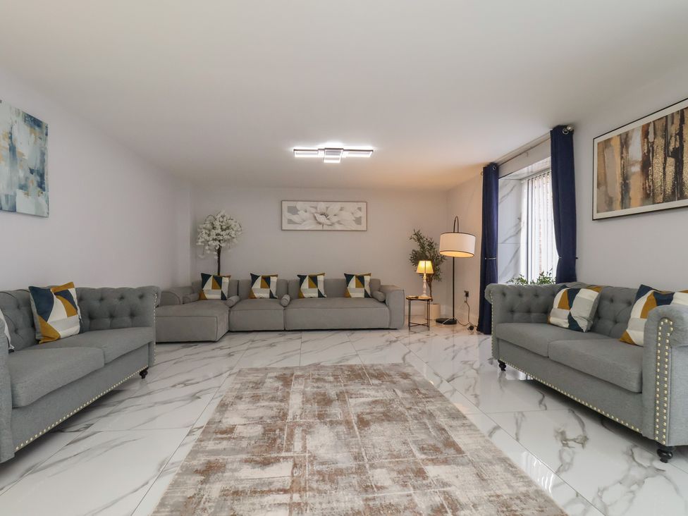 A living room with sofas, a lamp, and a rug at Courtenay House in Harpham near Nafferton