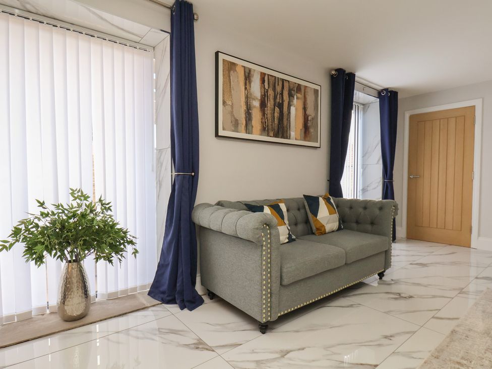 A living room with a sofa and a plant at Courtenay House in Harpham near Nafferton