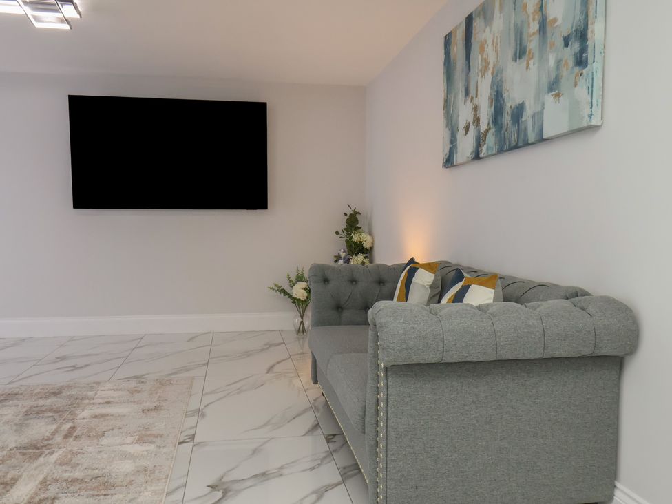 A living room with a sofa and wall-mounted TV at Courtenay House Harpham near Nafferton