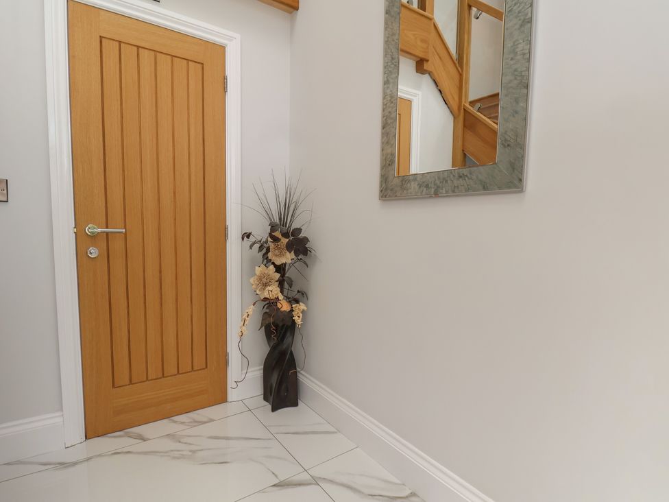 A hallway with a wooden door and a mirror at Courtenay House Harpham near Nafferton