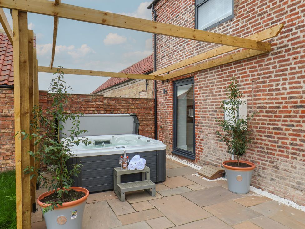 A garden with a hot tub and planters at Courtenay House in Harpham near Nafferton