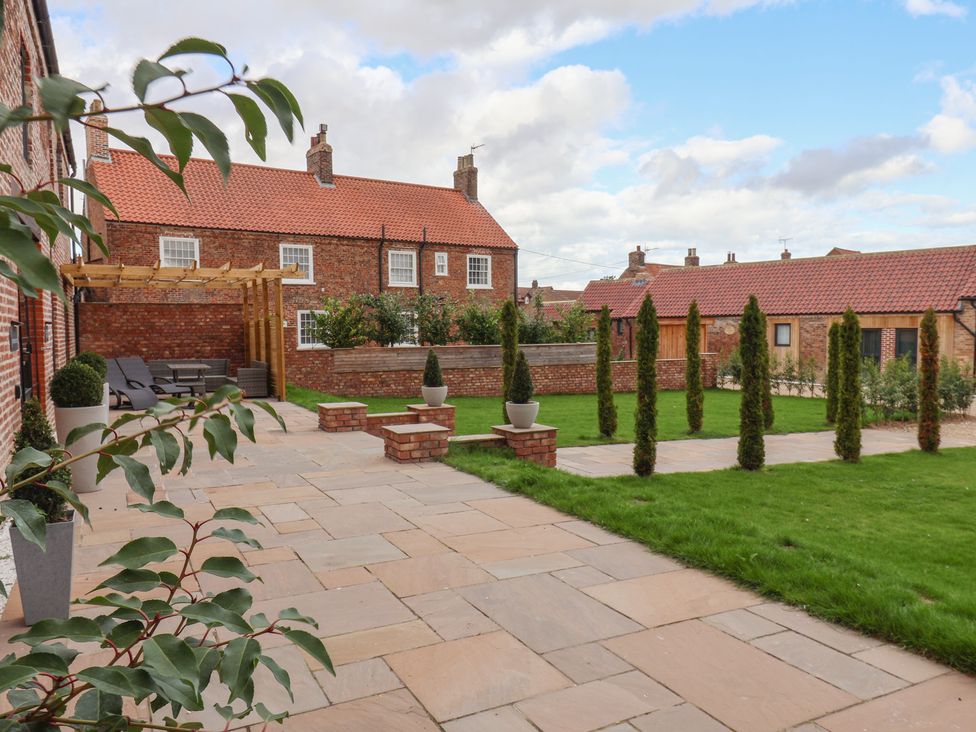 A garden with patio and shrubs at Courtenay House in Harpham near Nafferton