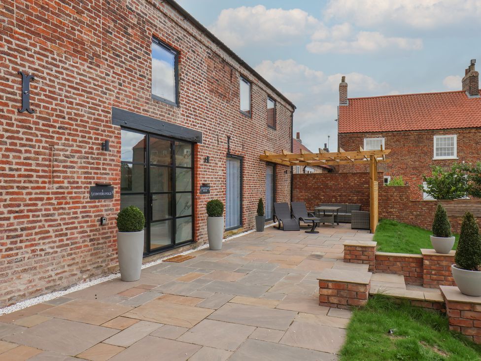 A patio with seating and planters at Courtenay House Harpham near Nafferton
