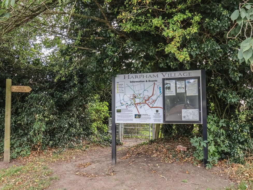 An information board with a map of Harpham Village and public footpath sign near Harpham near Nafferton