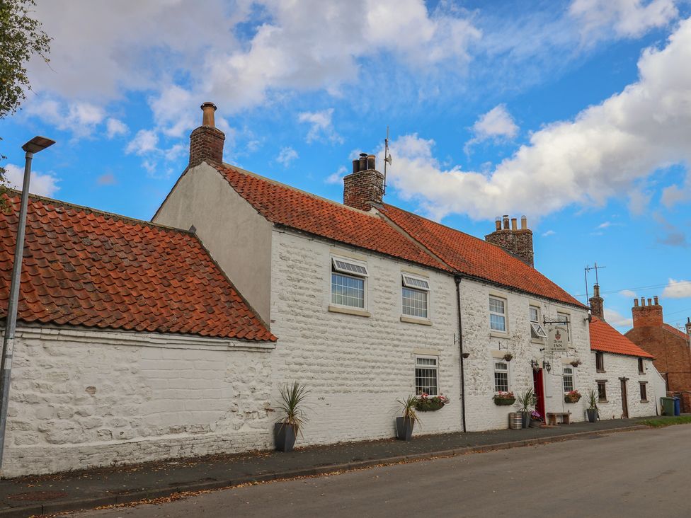 A building with a red roof and windows at Courtenay House Harpham near Nafferton