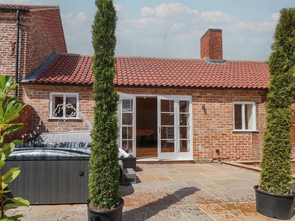 An outdoor view of a house with a hot tub and plants at Harpham Manor House in Harpham near Nafferton