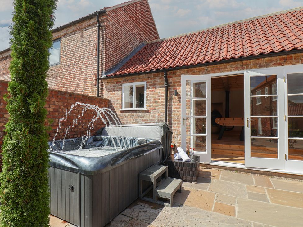 An outdoor space with a hot tub and patio area at Harpham Manor House in Harpham near Nafferton