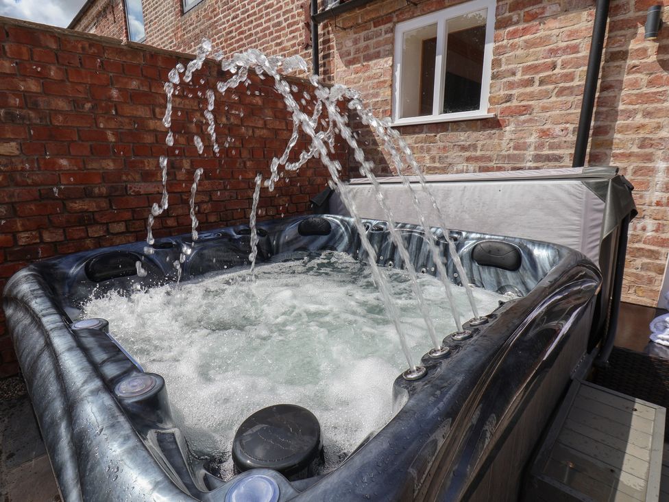 A hot tub with water jets in an outdoor space at Harpham Manor House in Harpham near Nafferton
