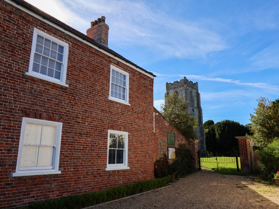 An exterior view of a brick house with a tower in the background at Harpham Manor House in Nafferton