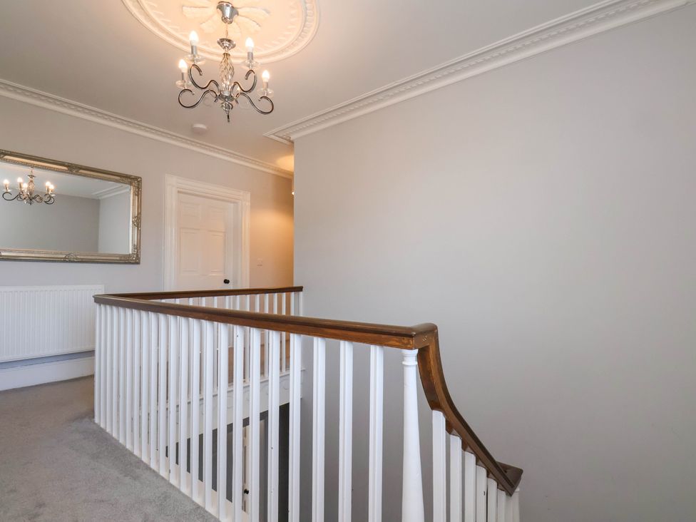 A hallway with a chandelier and a mirror at Harpham Manor House in Nafferton