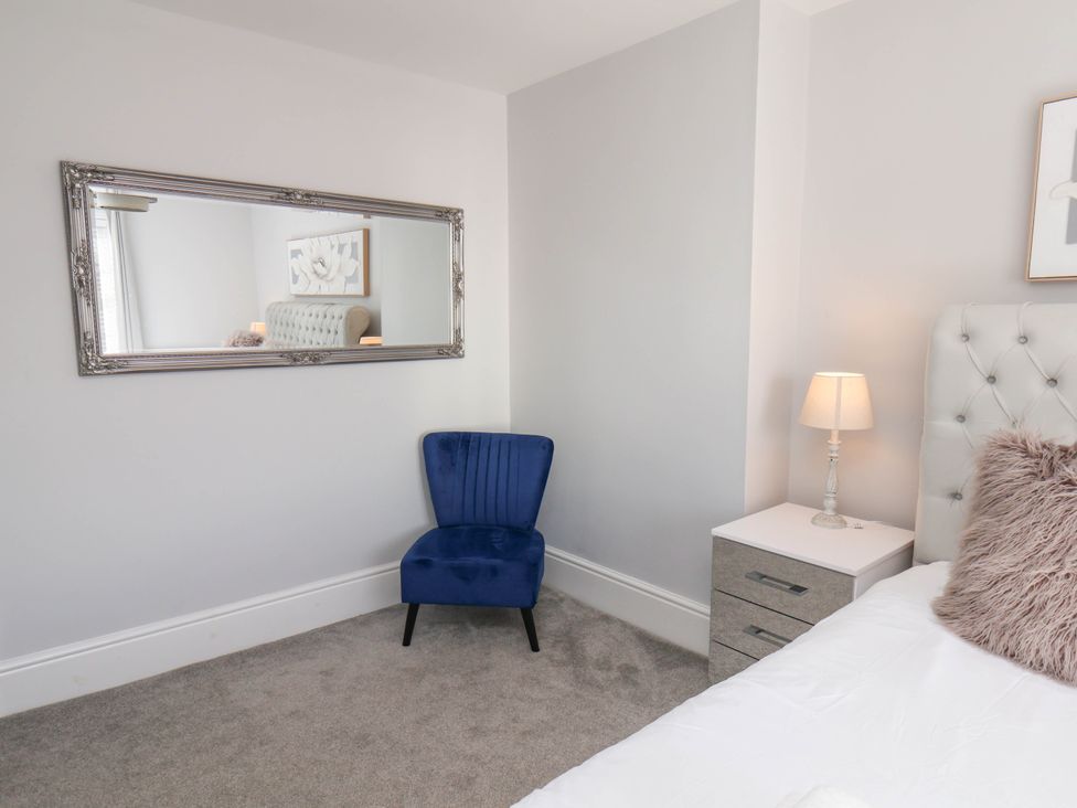 A bedroom with a blue chair and mirror at Harpham Manor House Nafferton