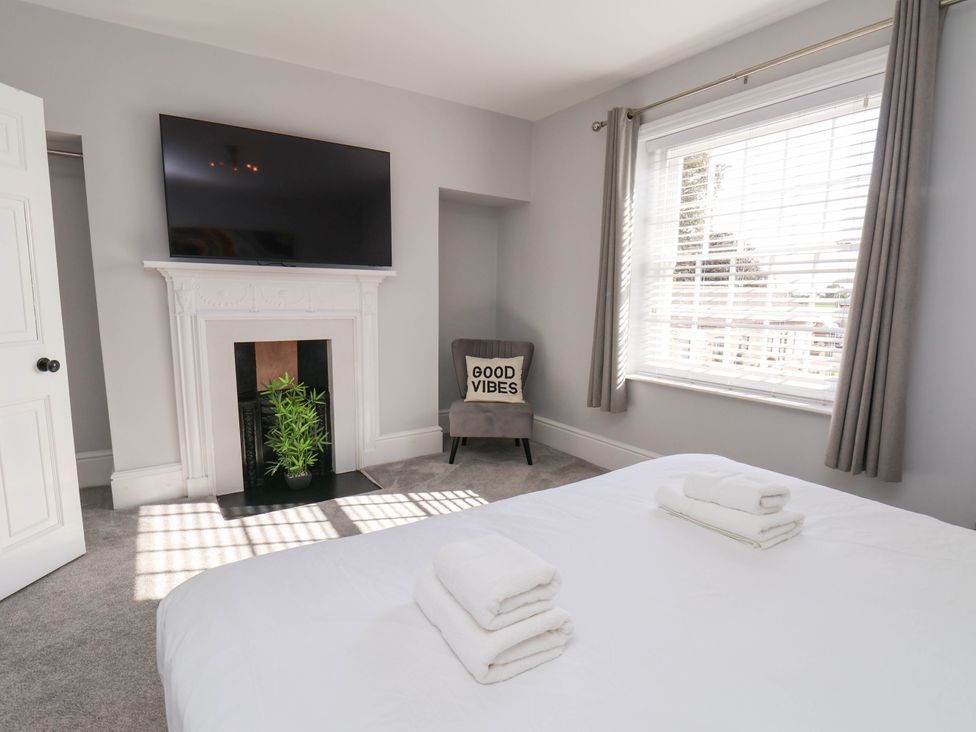 A bedroom with a television and towels on the bed at Harpham Manor House Nafferton