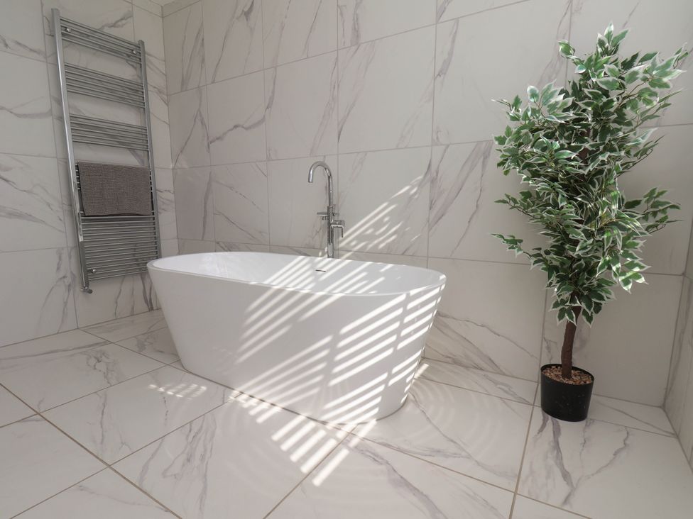 A bathroom with a bathtub and towel rail at Harpham Manor House, Nafferton