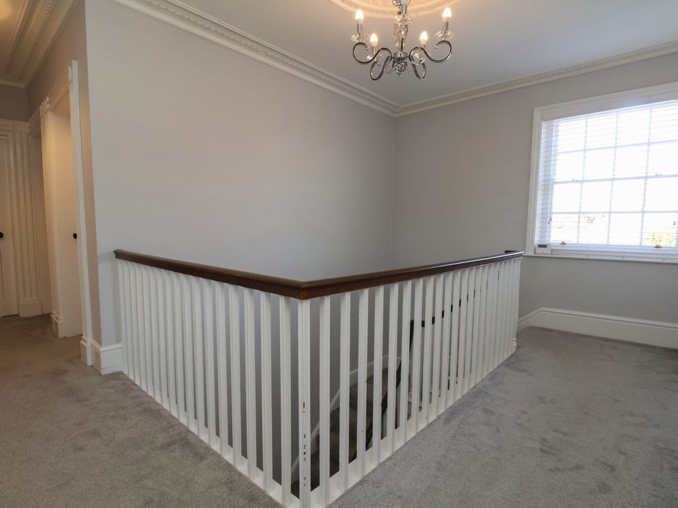 A hallway with a railing and chandelier at Harpham Manor House Nafferton