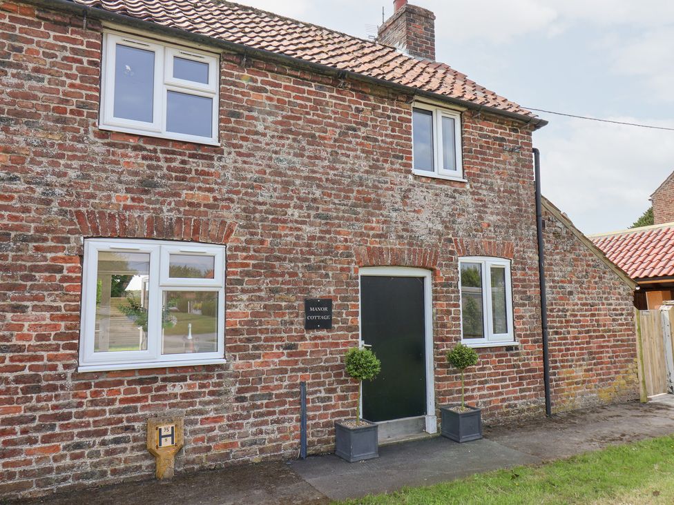 Exterior view of a brick house with windows and a door at Manor Cottage Harpham near Nafferton