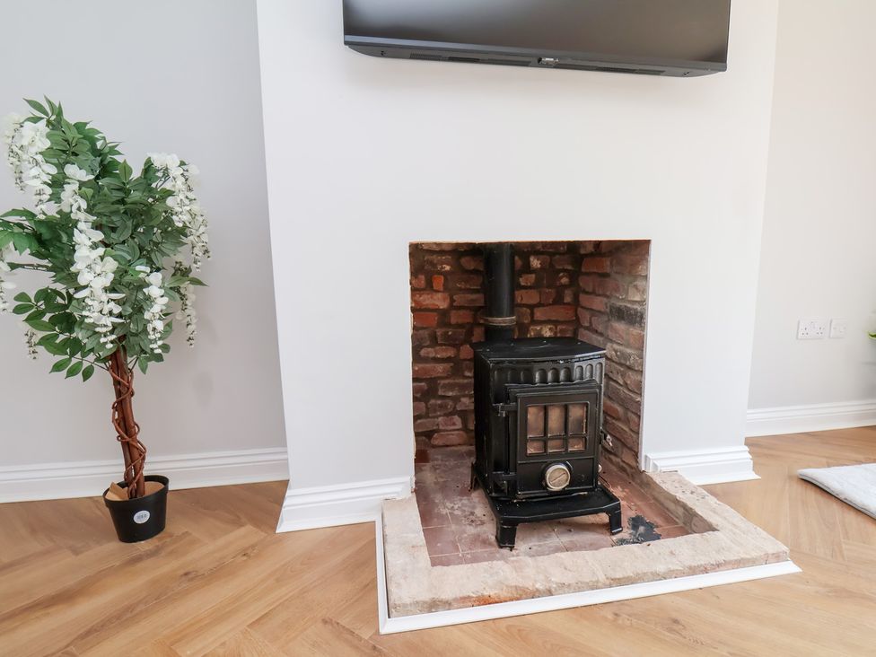 A living room featuring a fireplace and a television at Manor Cottage in Harpham near Nafferton