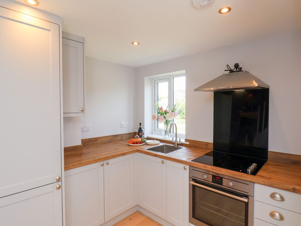 A kitchen with cabinets, a sink, stovetop, and a window at Manor Cottage in Harpham near Nafferton