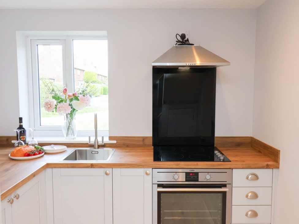 A kitchen with a stove, oven, sink, and flowers at Manor Cottage in Harpham near Nafferton