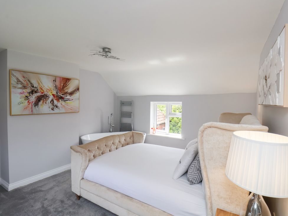 A bedroom with a bed and a bathtub at Manor Cottage in Harpham near Nafferton