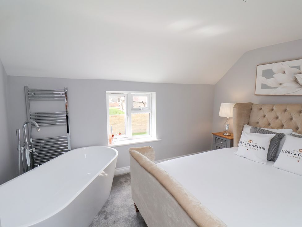 A bedroom with a bathtub and radiator at Manor Cottage in Harpham near Nafferton