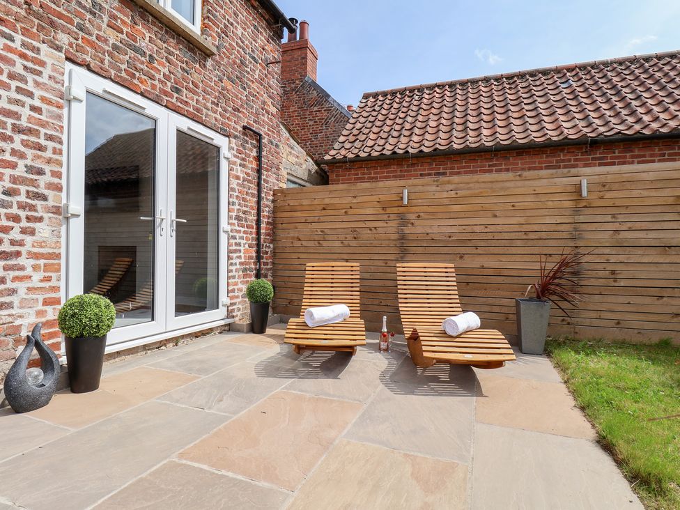 An outdoor area with deck chairs and a bottle at Manor Cottage Harpham near Nafferton