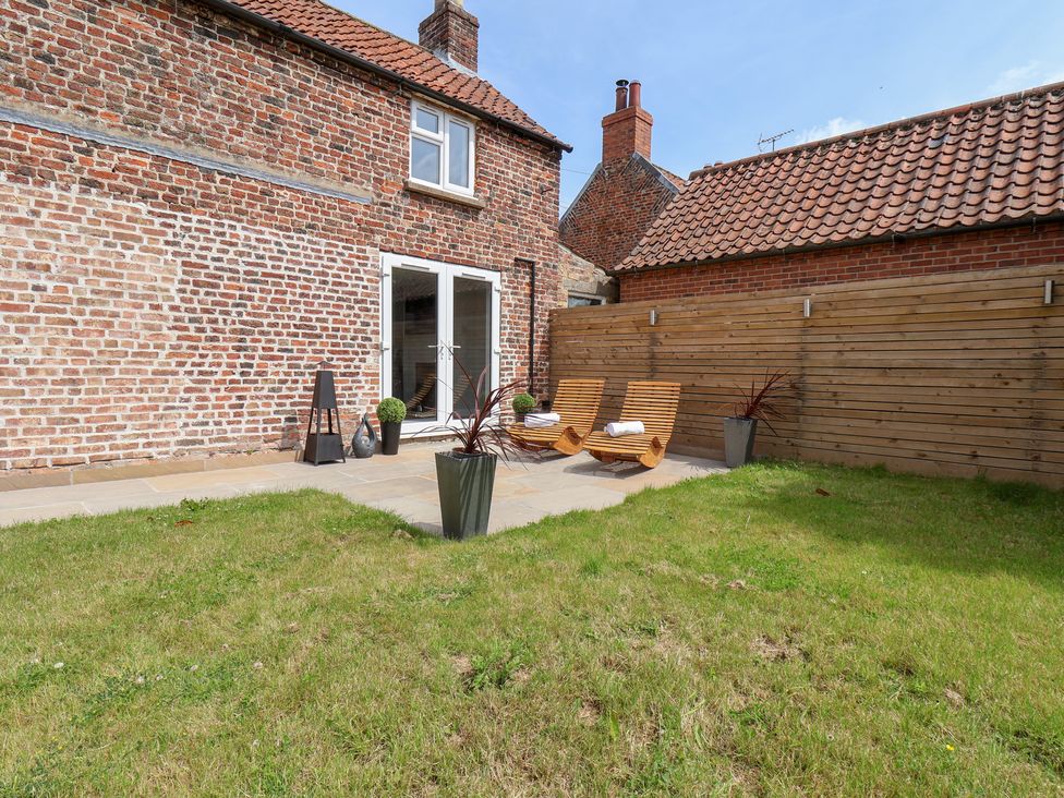 A garden with deck chairs and planters at Manor Cottage in Harpham near Nafferton