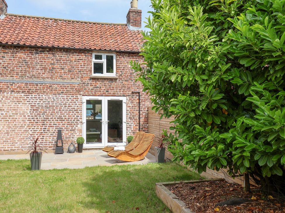 A garden with a lounge chair and potted plants at Manor Cottage in Harpham near Nafferton