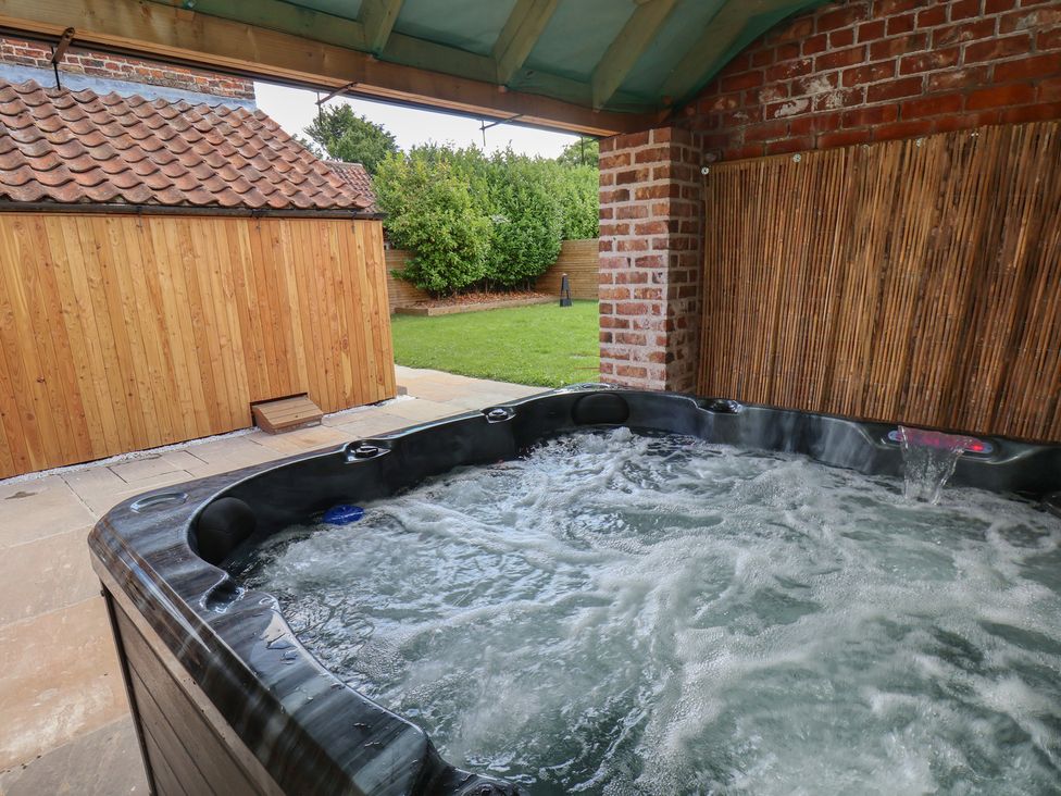 An outdoor area with a hot tub and wooden shed at Manor Cottage in Harpham near Nafferton