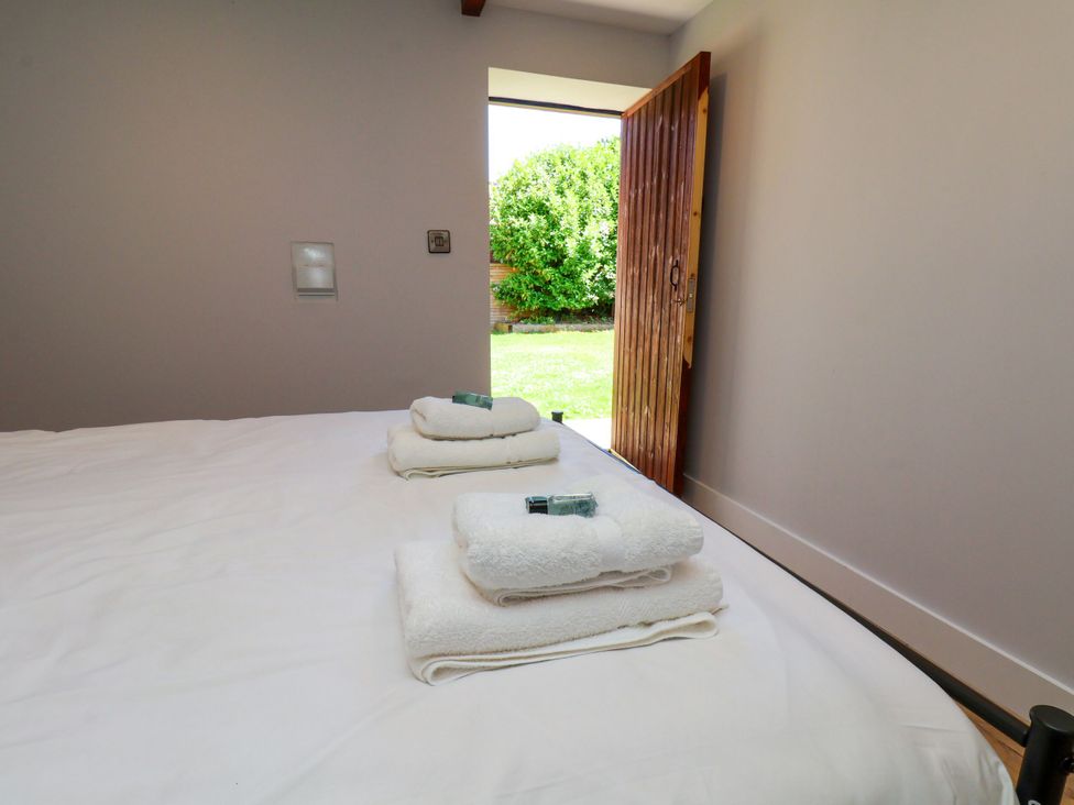 A bedroom with towels on the bed and a door leading to the garden at Manor Cottage in Harpham near Nafferton