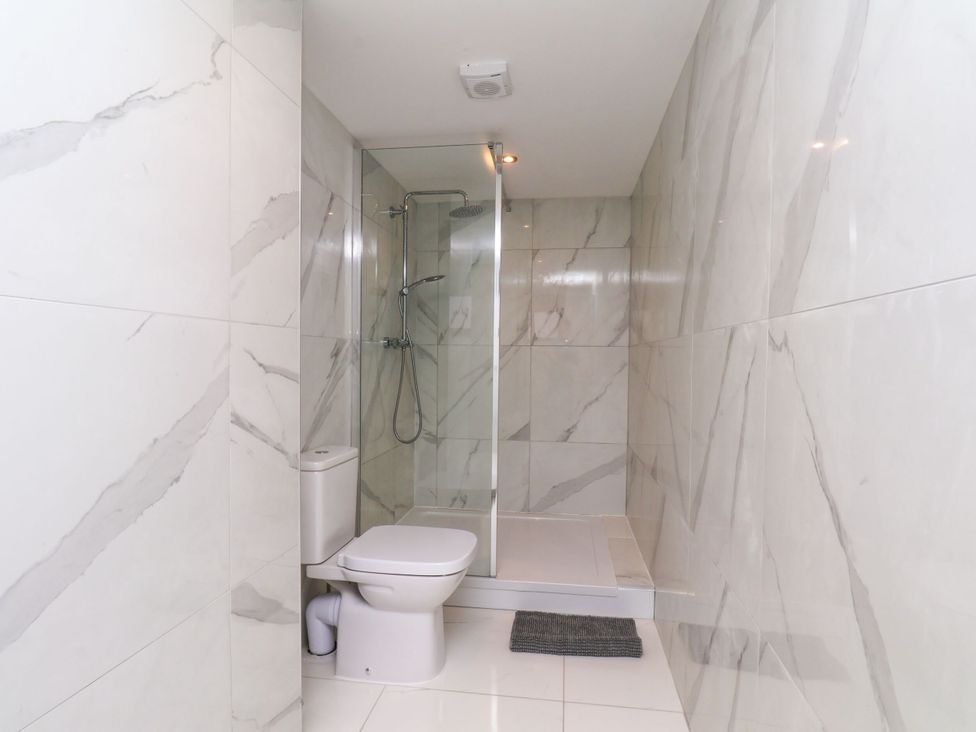 A bathroom with a shower, toilet and towel mat at Manor Cottage in Harpham near Nafferton