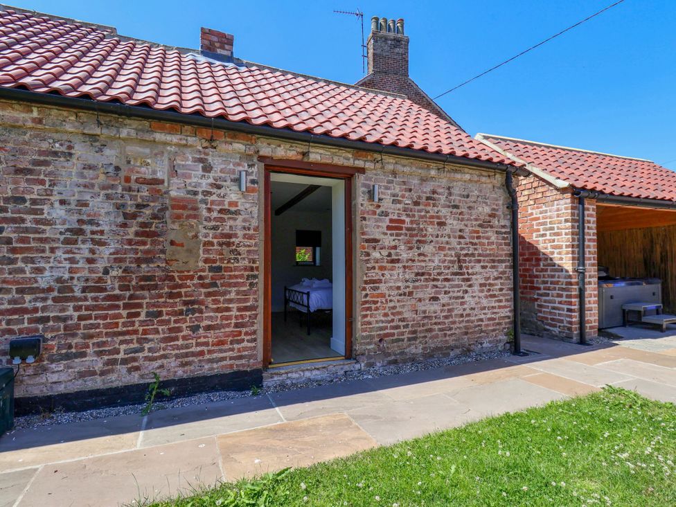 An outdoor area with a brick wall and door at Manor Cottage in Harpham near Nafferton