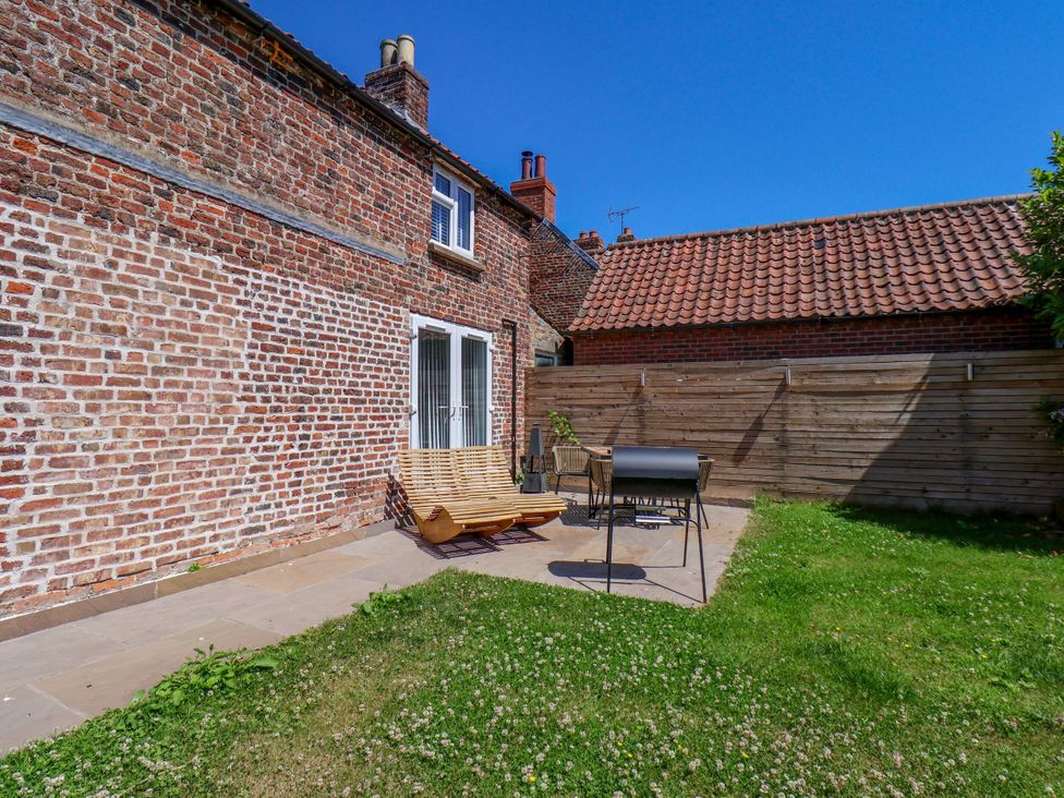 A garden with a patio and deck chair at Manor Cottage in Harpham near Nafferton