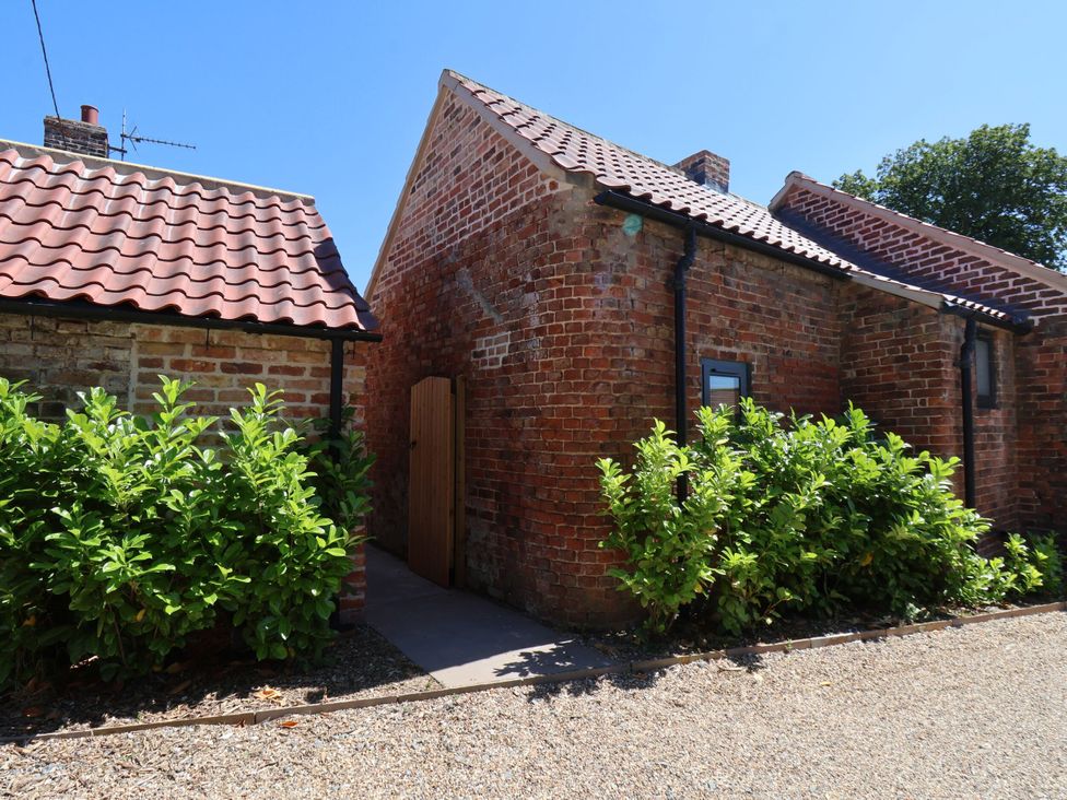 An outdoor view of a brick building with a path and foliage at Manor Cottage Harpham near Nafferton