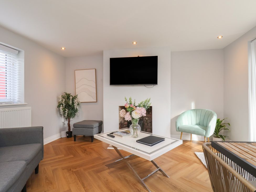 A living room with a television, sofa, coffee table, and flowers at Manor Cottage in Harpham near Nafferton