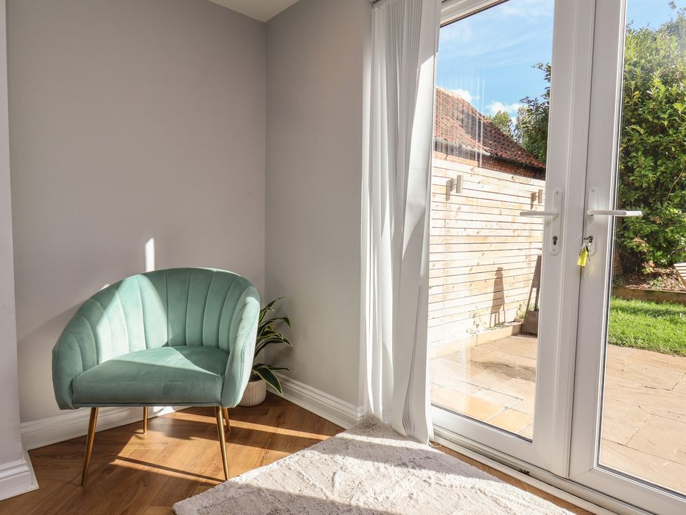 A garden room with a chair and a door leading to the outside at Manor Cottage Harpham near Nafferton