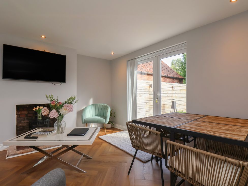 A living room with a television and dining table at Manor Cottage in Harpham near Nafferton