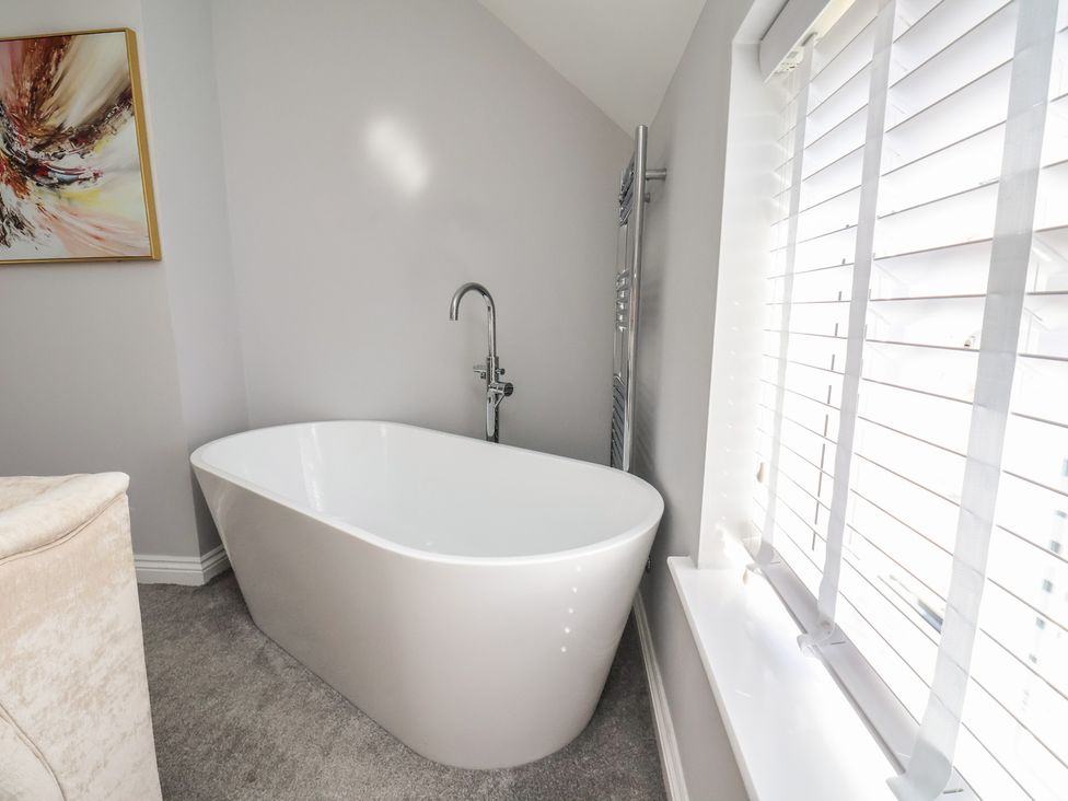 A bathroom with a bathtub and a towel radiator at Manor Cottage Harpham near Nafferton