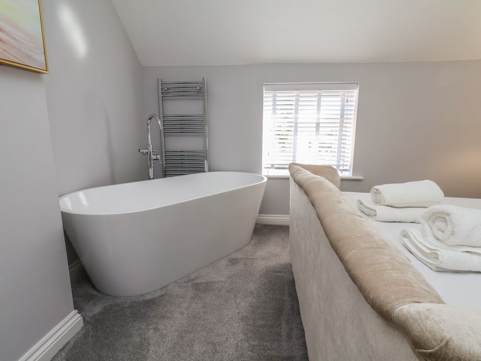 A bathroom with a bathtub and towels at Manor Cottage in Harpham near Nafferton