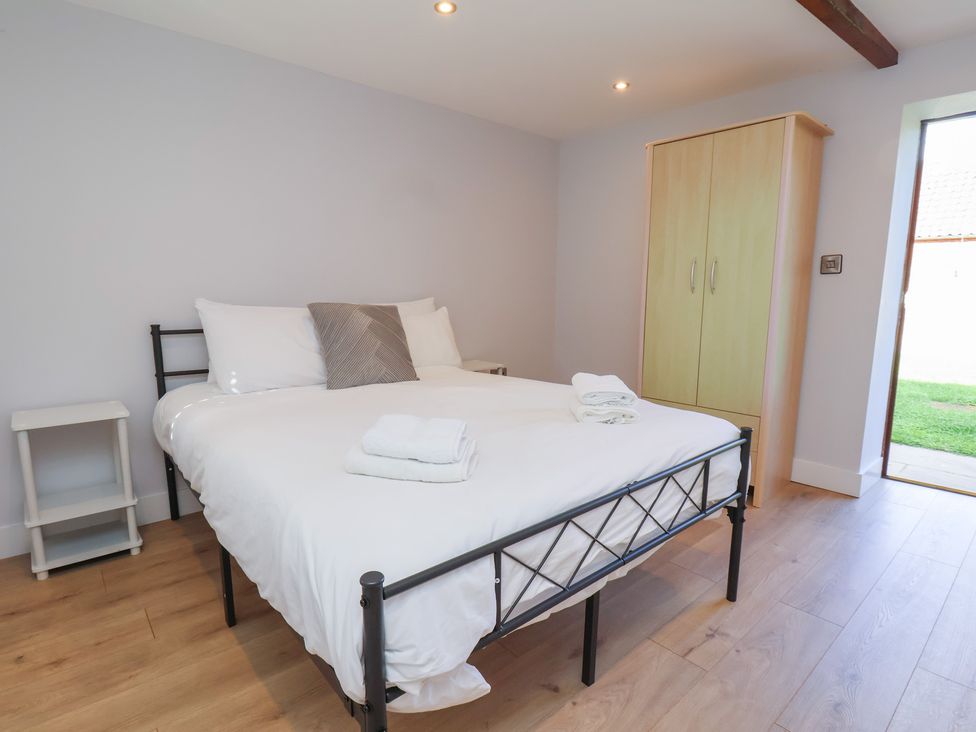 A bedroom with a bed and wardrobe at Manor Cottage in Harpham near Nafferton