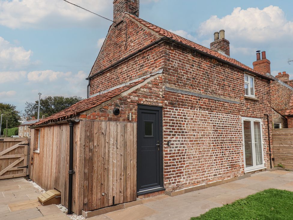An exterior view of a brick house with a garden at Manor Cottage in Harpham near Nafferton