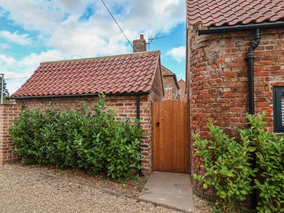 An outdoor area with a wooden door and brick walls at Manor Cottage in Harpham near Nafferton