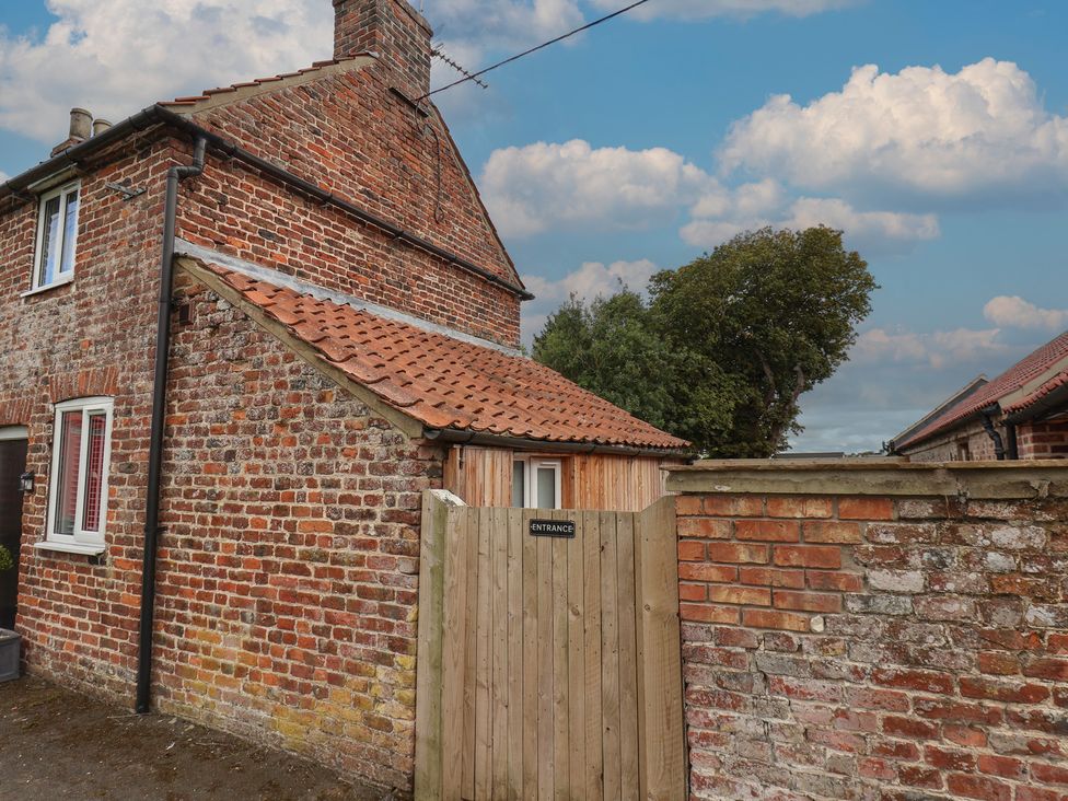 A brick house with a gate entrance at Manor Cottage in Harpham near Nafferton
