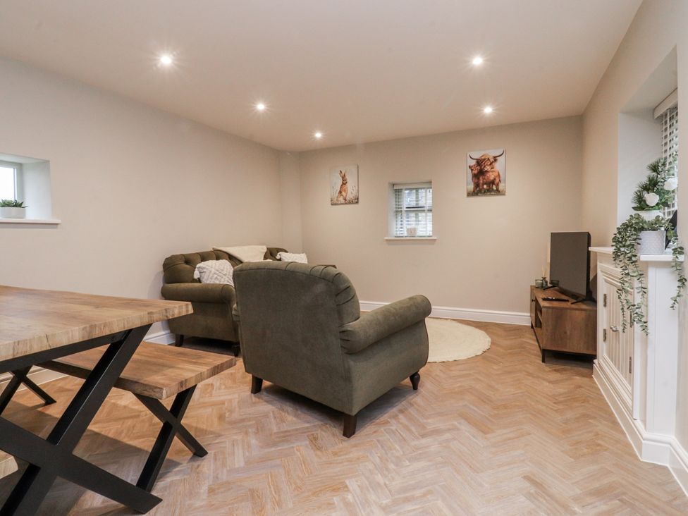 A living room with a sofa, dining table, and television at Henside Cottage in Settle
