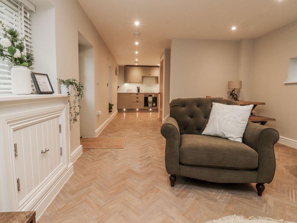 A living room with a sofa and kitchen area at Henside Cottage Settle