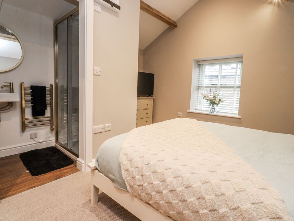 A bedroom with a bed, television, and en-suite bathroom at Henside Cottage Settle
