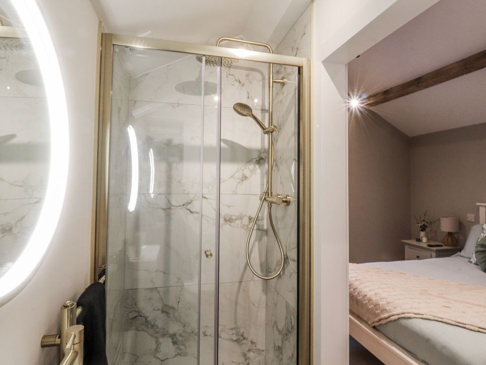 A shower enclosure with a towel rack and a bedroom visible at Henside Cottage in Settle